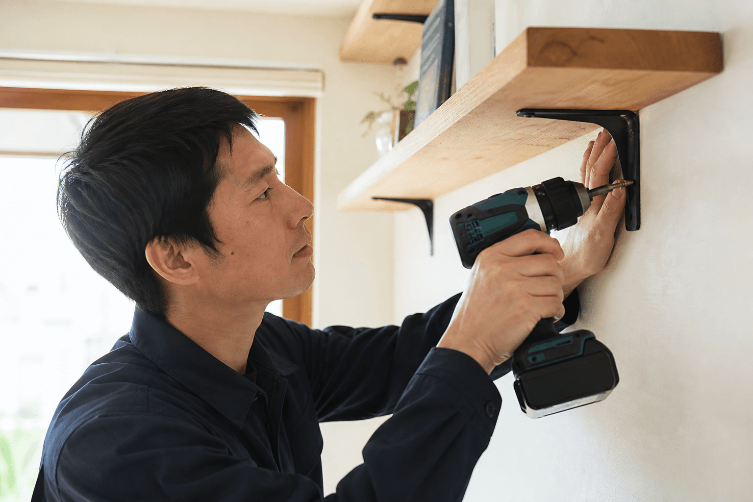 電動ドライバーで壁面の棚を取り付ける手元